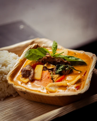 Röd curry gryta med kokosmjölk, nötkött och thaibasilika i takeaway-box med ris